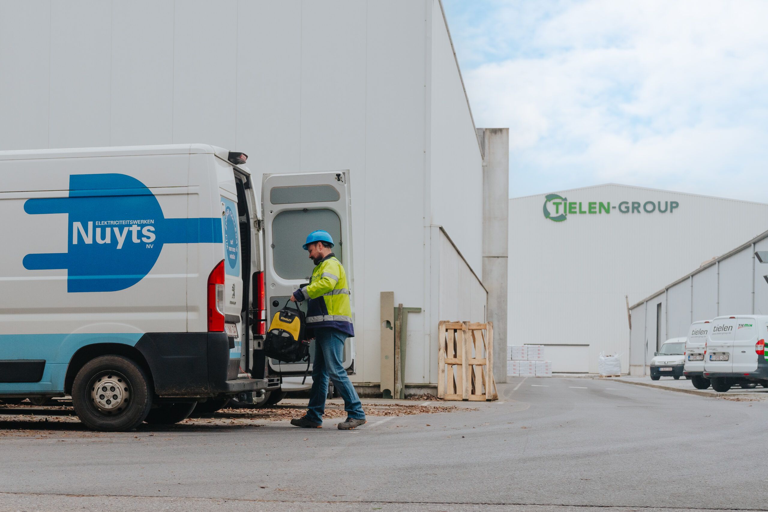 Technieker van Elektriciteitswerken Nuyts aan de bestelwagen op een werf